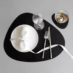 Black leaf-shaped leather placemat and coaster set.
