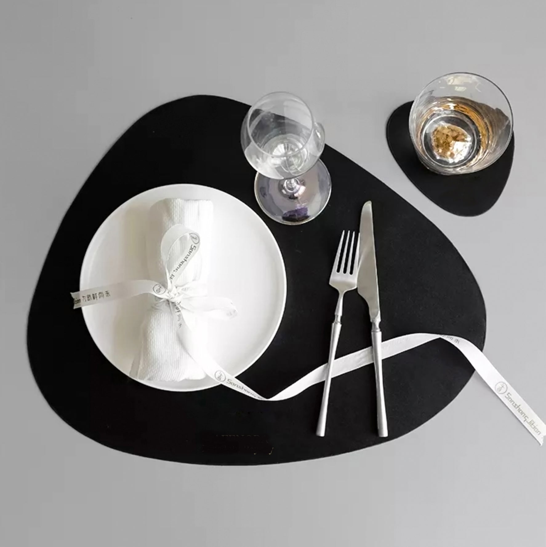 Black leaf-shaped leather placemat and coaster set.