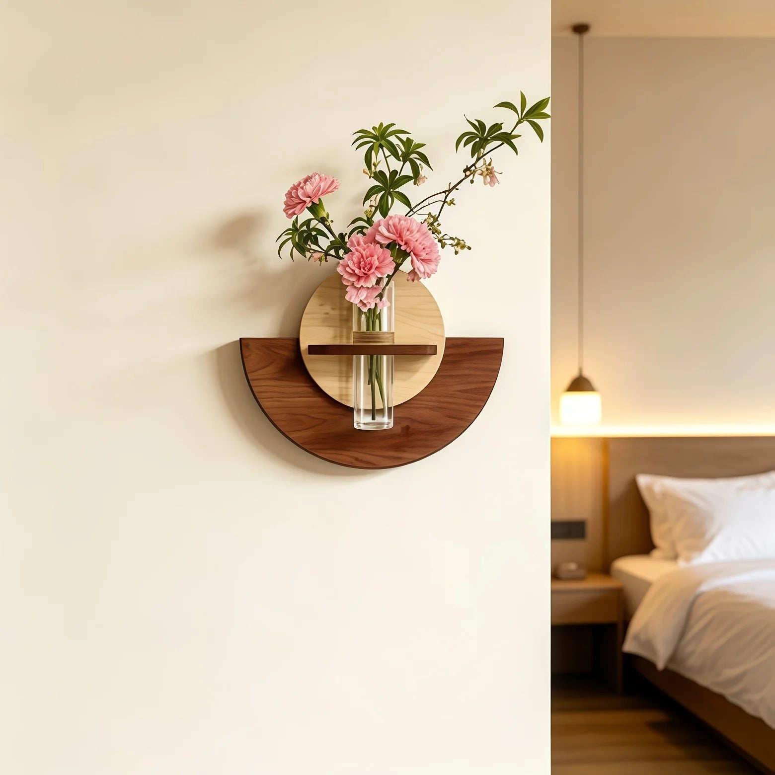 A wall-mounted wooden shelf and vase holder with pink flowers, shown mounted on an off-white wall in a softly lit bedroom setting.