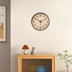 Round, wood-grain wall clock with black frame and Arabic numerals.