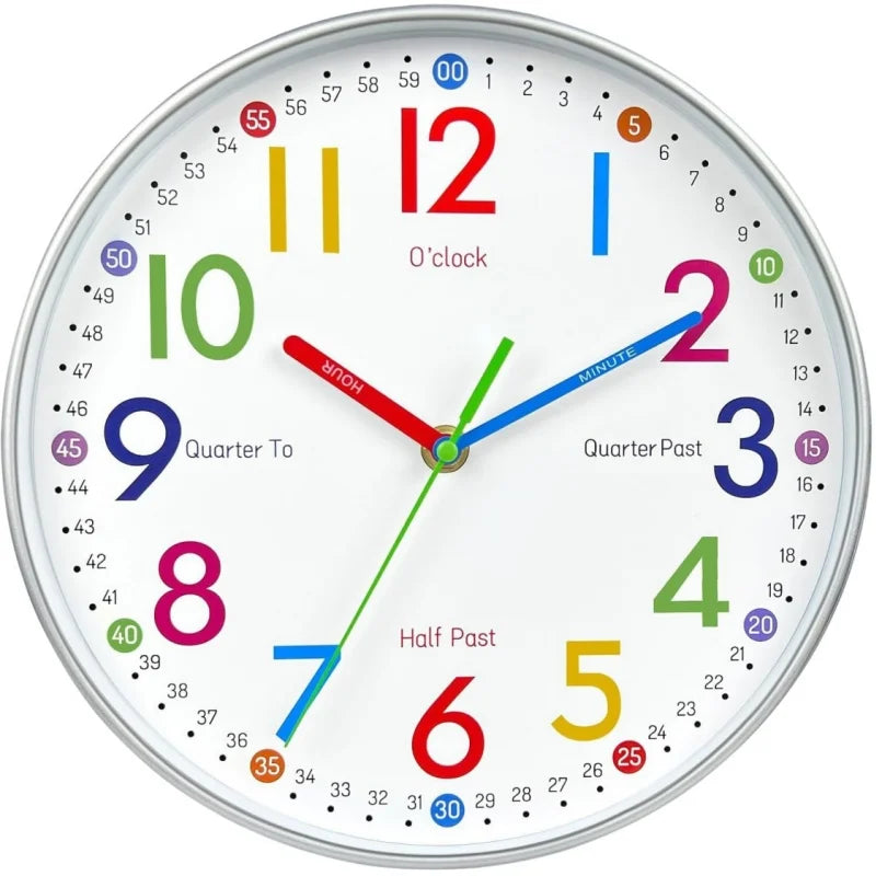 A round children's wall clock with a white face, silver rim, and colorful numerals and hands. The numbers 1 through 12 are in different bright colors, with smaller black minutes and additional time markers around the inner ring.