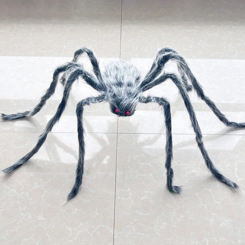 A large fake spider decoration with long hairy legs and red eyes, placed on a light beige tiled floor.