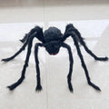 A large black hairy spider toy with red eyes, displayed on a light beige tiled floor.