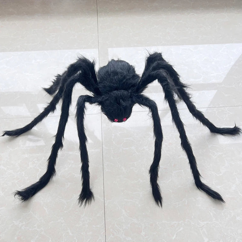 A large black hairy spider toy with red eyes, displayed on a light beige tiled floor.