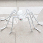 A white faux-fur spider Halloween decoration with red eyes, placed on a light beige tiled floor.