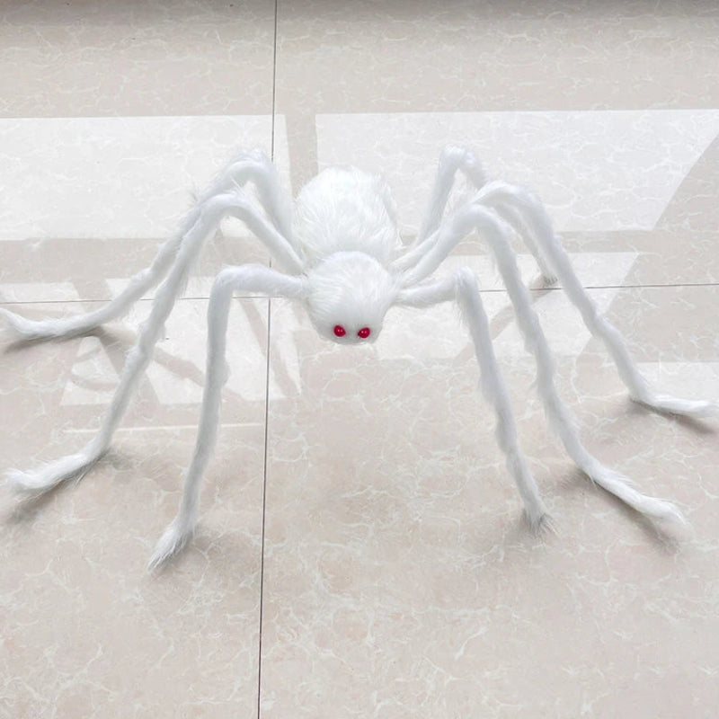 A white faux-fur spider Halloween decoration with red eyes, placed on a light beige tiled floor.