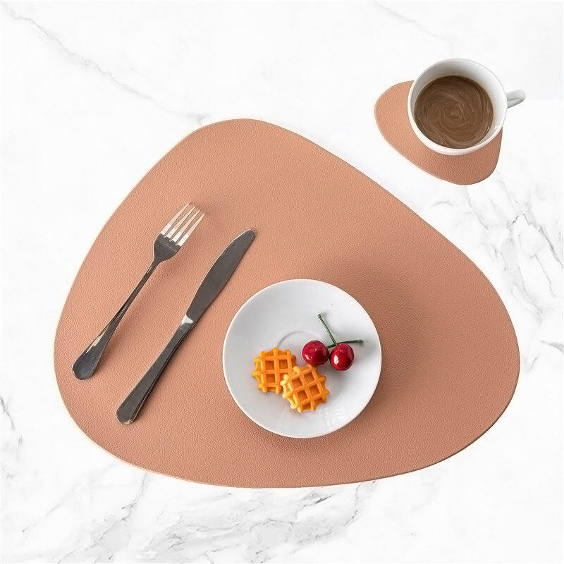 Brown leather placemat and coaster set with a modern, organic shape.
