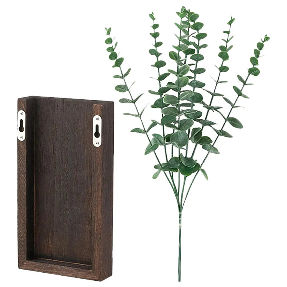 Dark brown wooden wall planter with two keyhole hangers on the back, next to a bunch of green faux eucalyptus stems.