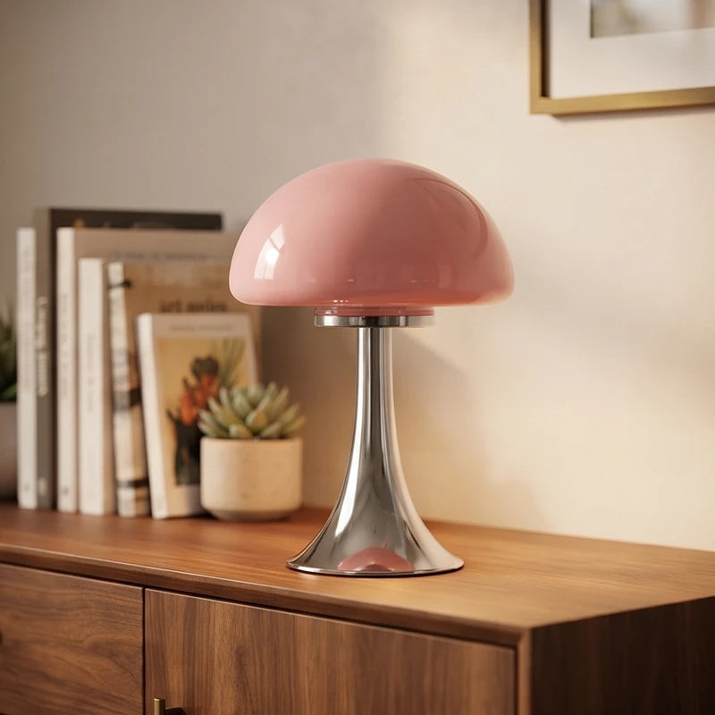 Glossy pink mushroom-shaped table lamp with a reflective silver base sits on a wooden credenza.