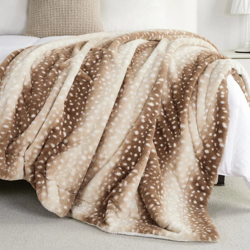 Soft faux fur throw blanket with brown and cream deer fawn spots draped over a bed with white sheets.