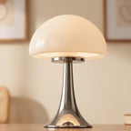 Mushroom-shaped table lamp with a creamy opal glass shade and a shiny, flared chrome base on a wooden surface.