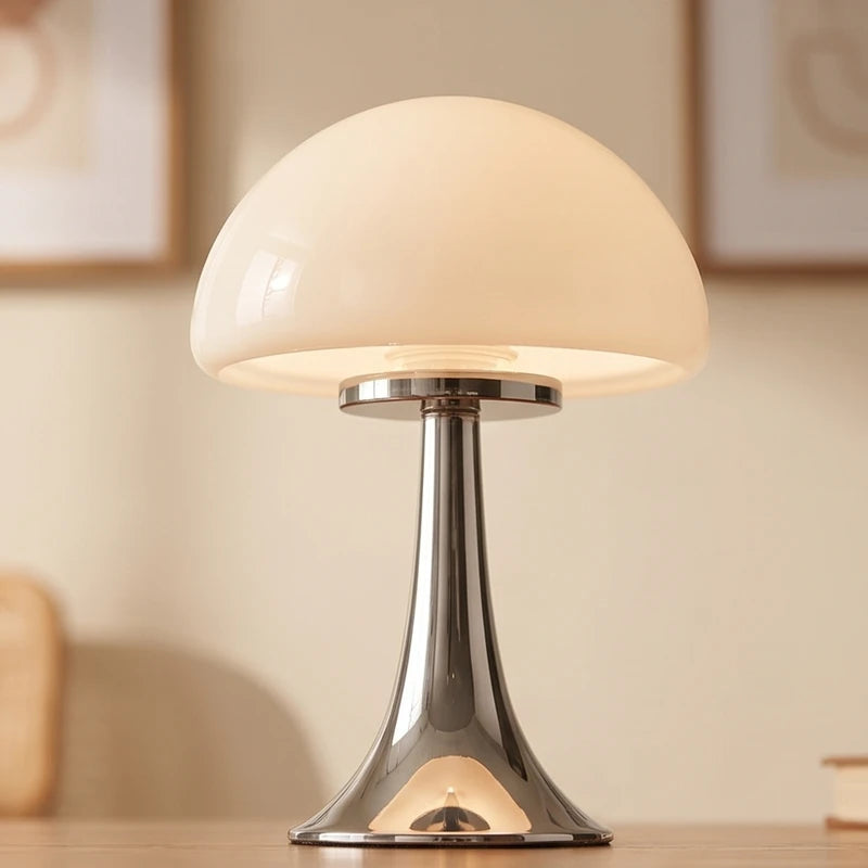Mushroom-shaped table lamp with a creamy opal glass shade and a shiny, flared chrome base on a wooden surface.